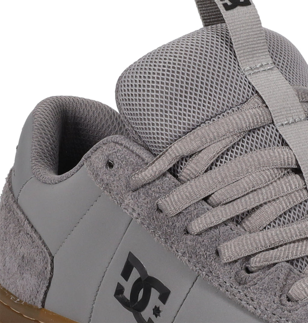Close-up of the Men’s Astrix Shoes by DC Shoes in gray, featuring suede and mesh details, visible laces, and the iconic DC logo on the side—designed for superior board control during street skateboarding.