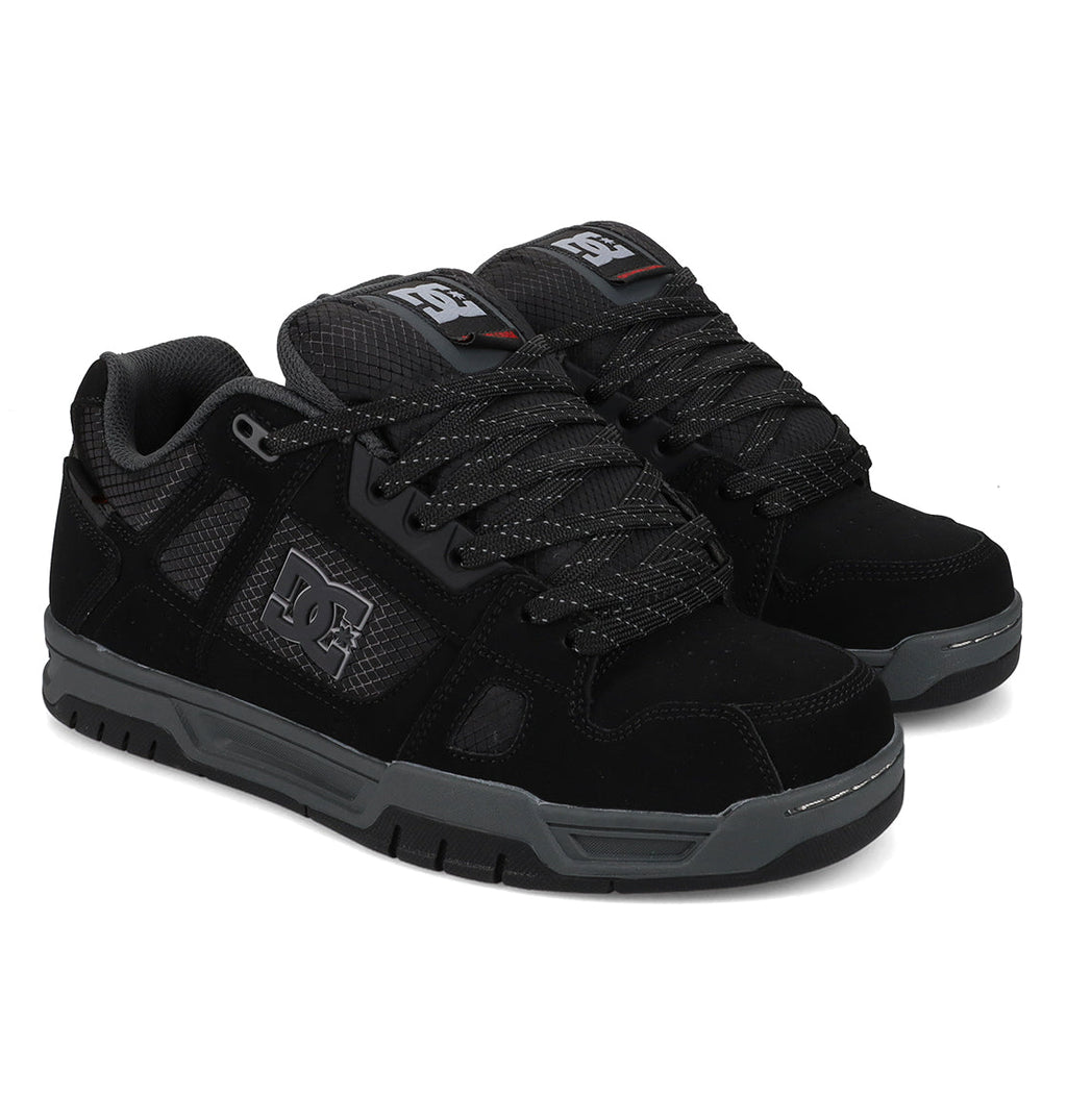 A pair of Men’s Stag Winterized Shoes by DC Shoes in black, designed with gray soles and textured leather panels. These shoes feature the DC Shoes logo on the side, black laces with gray accents, padded tongues, and lightweight cushioning for excellent impact absorption.