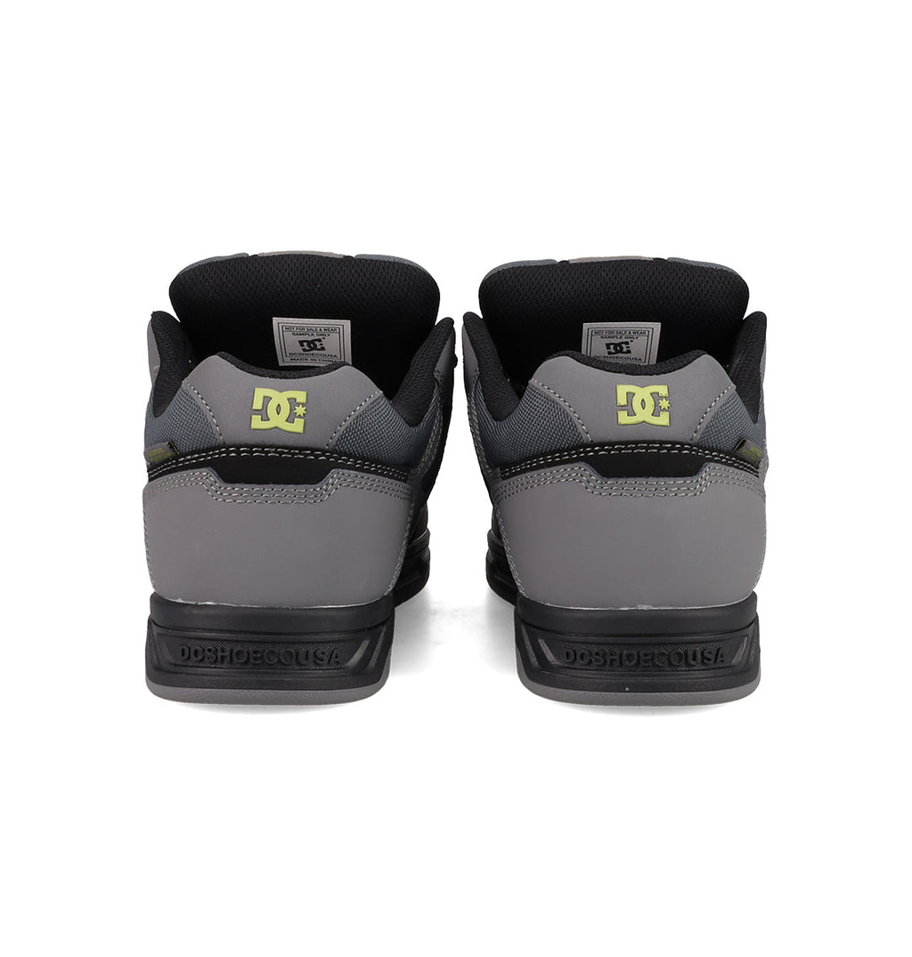 A rear view of Men's Stag Shoes by DC Shoes in grey and black, showing a yellow DC logo on the heels, DCSHOECOUSA on the midsoles, and a skate-inspired durable cupsole.