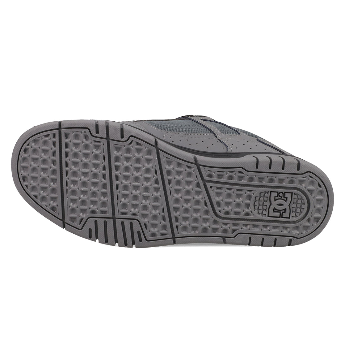 The image shows the gray rubber sole of DC Shoes Men's Stag Shoes, featuring geometric tread patterns for grip, a durable cupsole design, and the DC logo by the heel—ideal for skate culture fans.