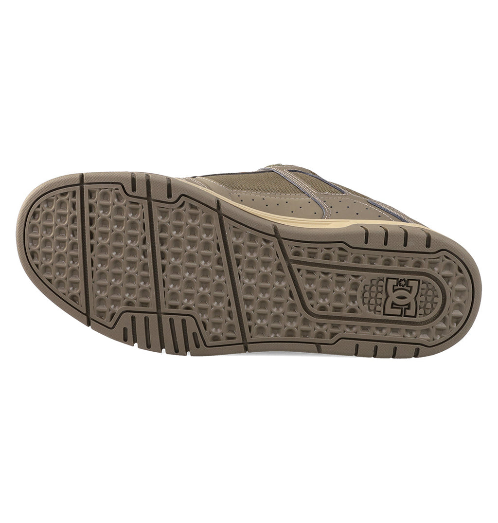 The image displays the sole of a brown DC Shoes Men's Stag Shoe with a geometric tread pattern, DC logo by the heel, and cupsole construction. The shoe is positioned on its side to clearly show the bottom view.