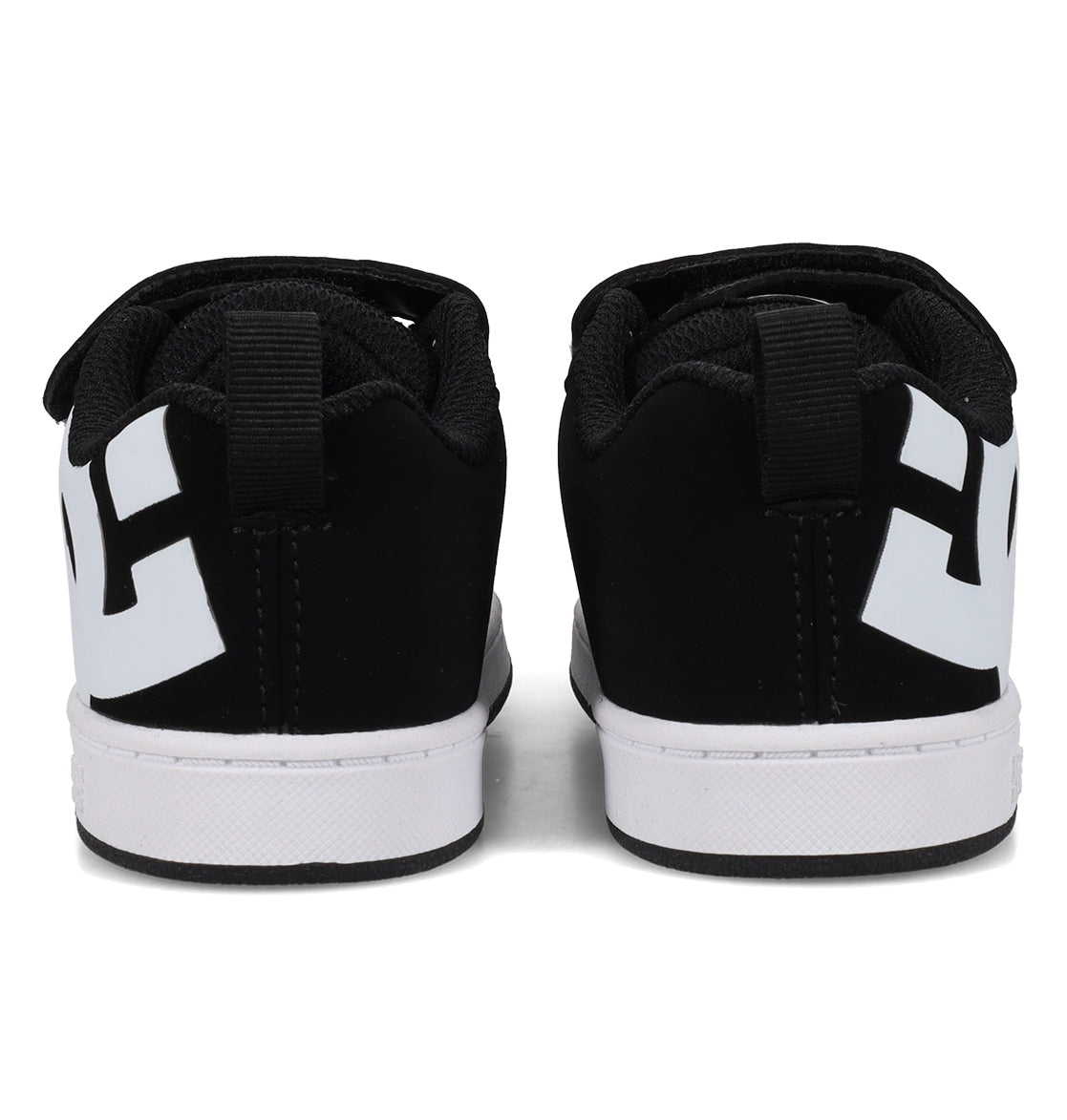 A pair of DC Shoes Kids’ Court Graffik Shoes – Toddler in black, viewed from the back. These sneakers feature a puffy, classic Court Graffik-inspired silhouette with thick white soles, bold white geometric designs on the heels, and black pull tabs at the top of the heel area.