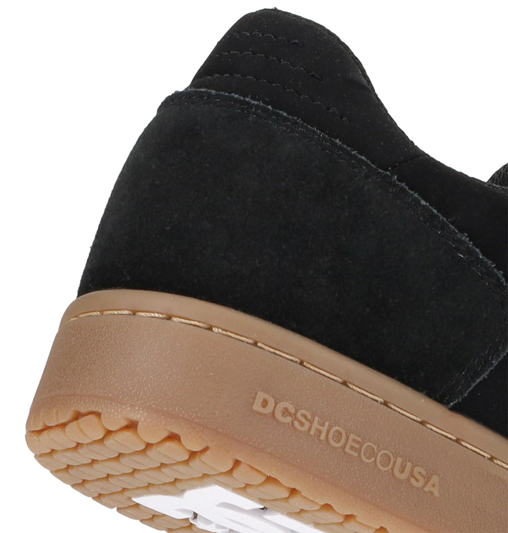 Close-up of the heel of the Men’s Astrix Shoe by DC Shoes, featuring black suede construction and a brown rubber sole designed for superior board control. The text “DCSHOECOUSA” is printed along the side of the sole, underscoring its authentic street skateboarding heritage.
