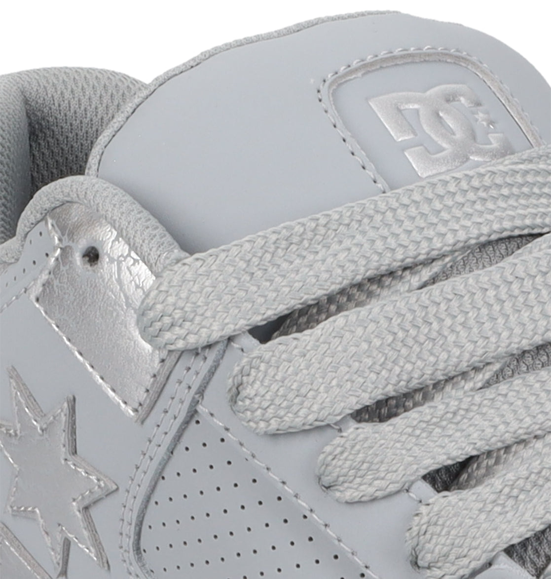 Close-up of the Women’s Command Shoes by DC Shoes in light gray, featuring textured laces, perforated details, a star emblem, and the DC logo embossed on the tongue—combining signature cushioning with unmistakable old-school energy.