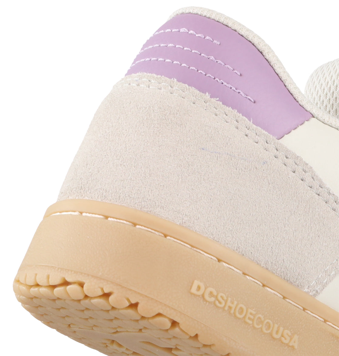 Close-up of the heel of the Women’s Astrix Shoes by DC Shoes, featuring a beige suede upper, a light tan rubber sole, and a lavender accent on the back. Designed for skateboarding, these shoes offer enhanced board control for street skating. DCSHOECOUSA is embossed on the side of the sole.