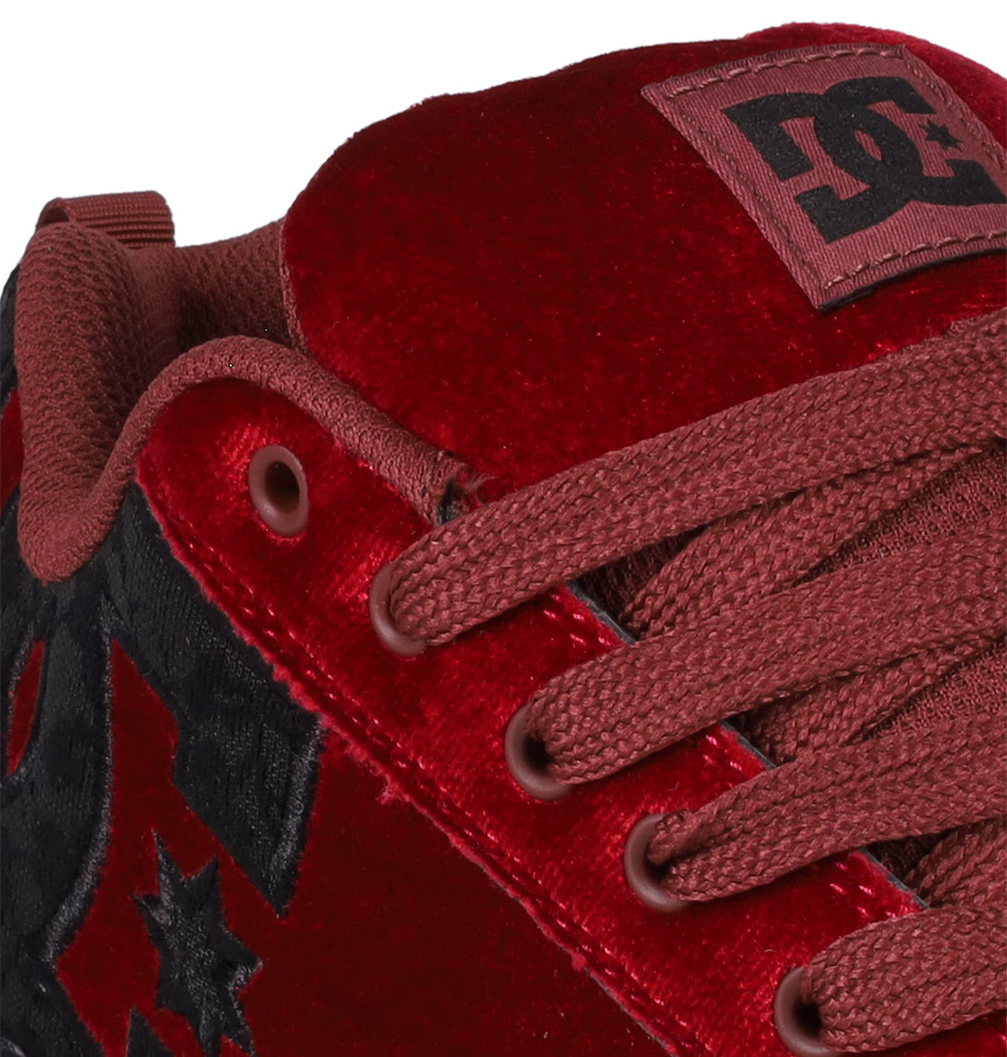 Close-up of the Women's Court Graffik LE Shoes by DC Shoes, showcasing red velvet with matching laces, the signature logo on the tongue, black patterned side accents, and a premium puffy silhouette in on-trend colors.