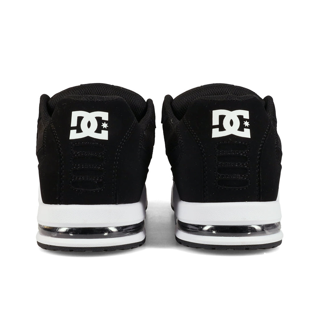 A pair of black Men’s AT-2 Shoes by DC Shoes viewed from the back, showcasing the signature white DC logo on the heel and white midsoles with a translucent accent above the outsole. Engineered for breathable comfort, these skate shoes keep your feet cool and supported throughout every session.
