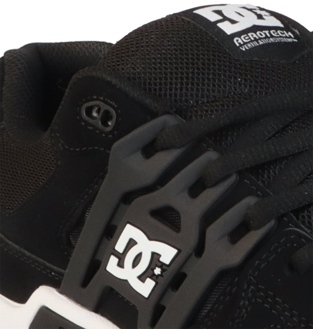 Close-up of a black DC Shoes Men’s AT-2 shoe showcasing the white DC logo on the side, black laces, breathable mesh fabric, and Agrotech branding on the tongue.