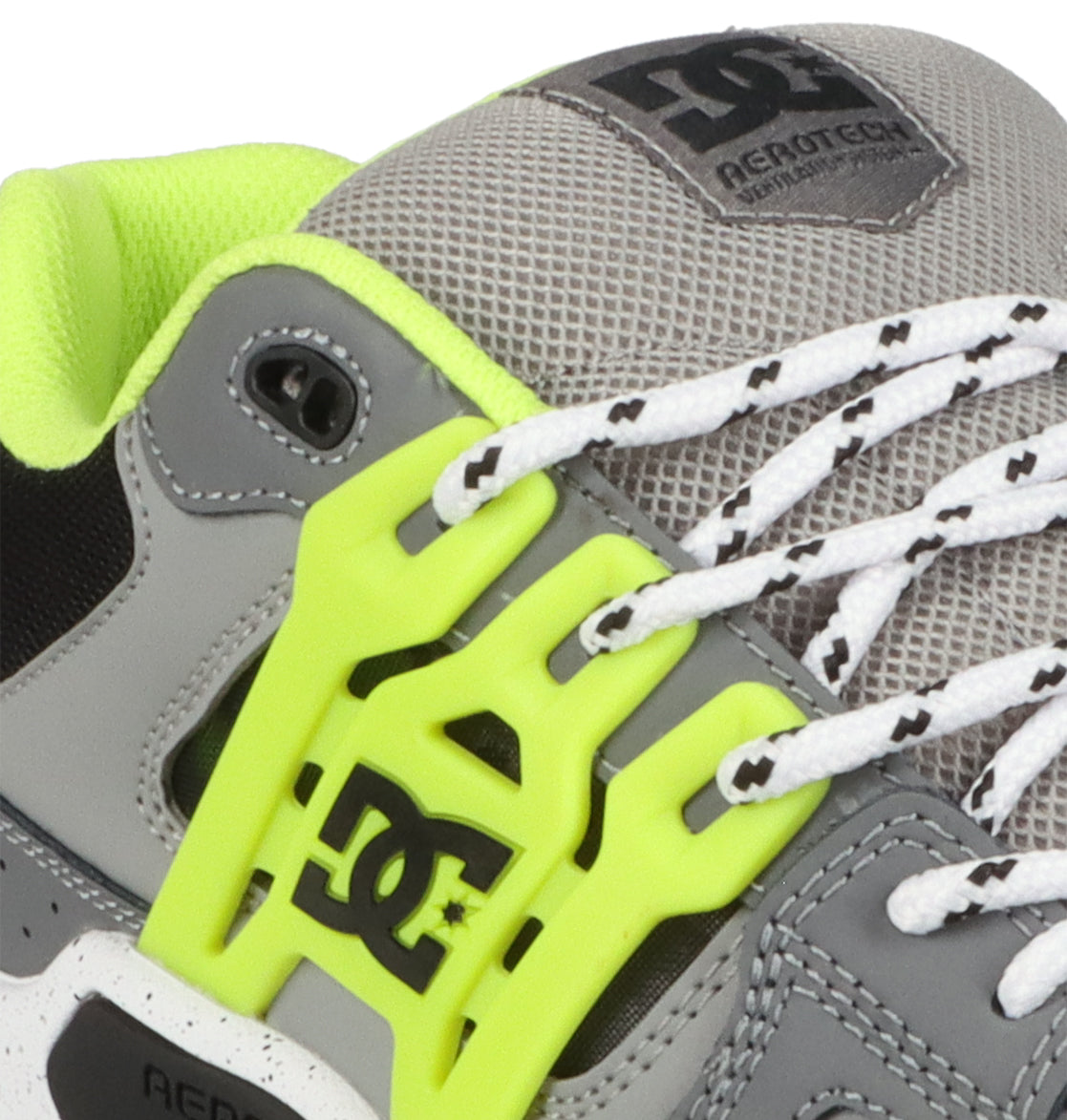 Close-up of a gray and neon yellow DC Shoes Men’s AT-2 sneaker, featuring mesh fabric with an AEROTECH ventilation system, white patterned laces threaded through a neon lace holder, a supportive TPU cage for added stability, and the DC logo displayed on the side and tongue.