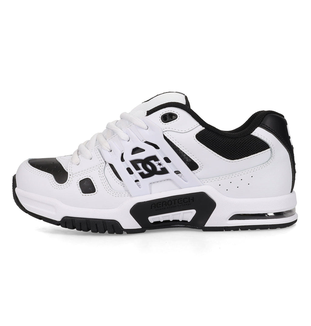 A side view of the DC Shoes Men’s AT-2 Shoes in white and black is shown, featuring mesh and leather panels, a thick airband outsole for enhanced traction, and the signature DC logo on the side.