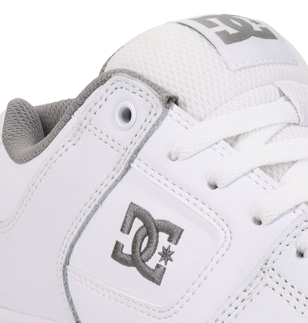 A detailed look at the Women’s Pure Shoes from DC Shoes showcases a white sneaker accented with gray, displaying the embroidered DC Shoes logo on the side and a printed logo on the tongue. The design features white laces and a padded gray interior, delivering lightweight cushioning for increased comfort and excellent impact absorption with each step.