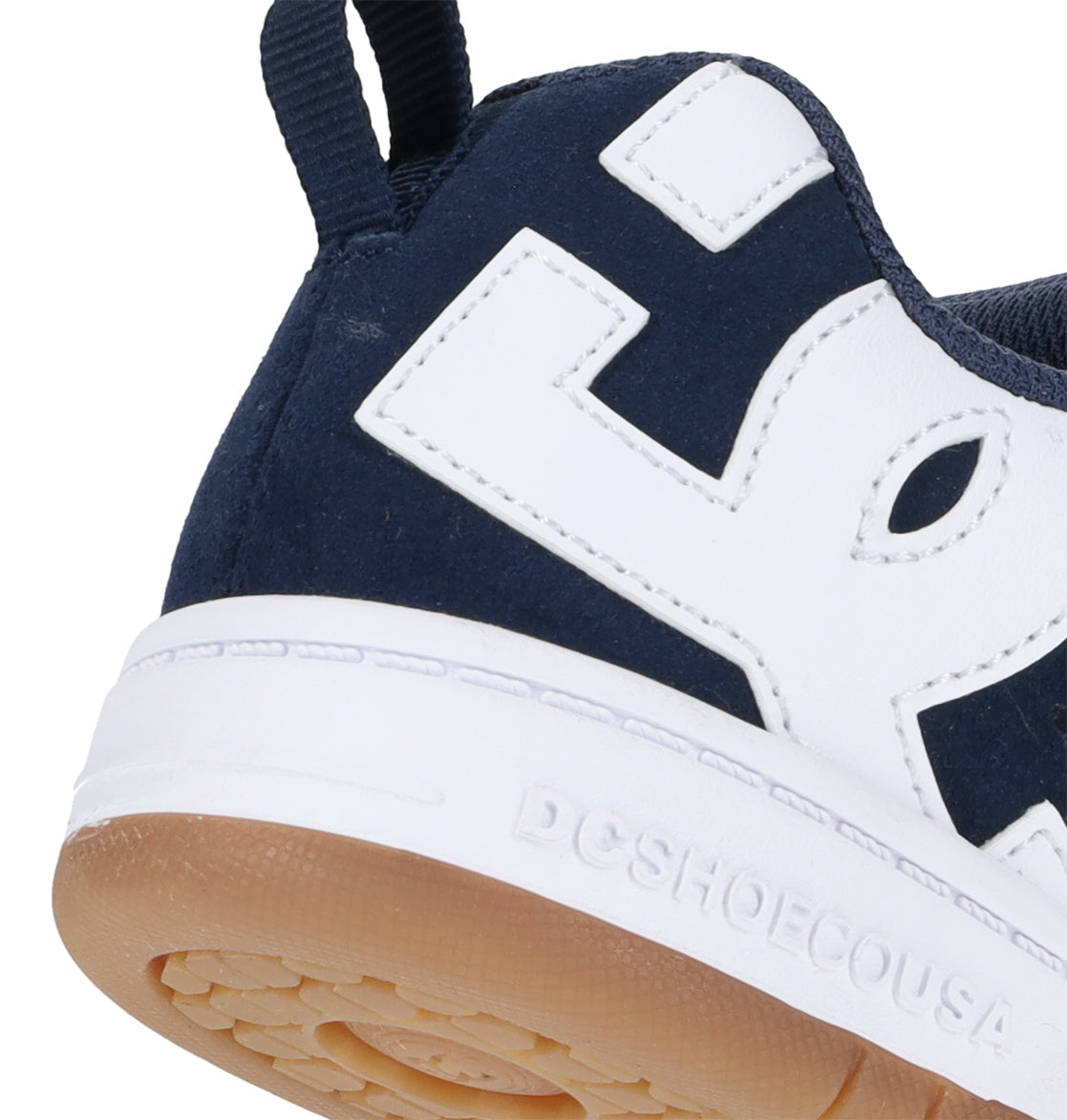 Close-up of the heel of a navy blue and white Kids’ Court Graffik Shoe by DC Shoes, featuring a gum sole. This sneaker showcases a puffy silhouette, oversized white branding, and DCSHOECOUSA embossed on the white midsole.