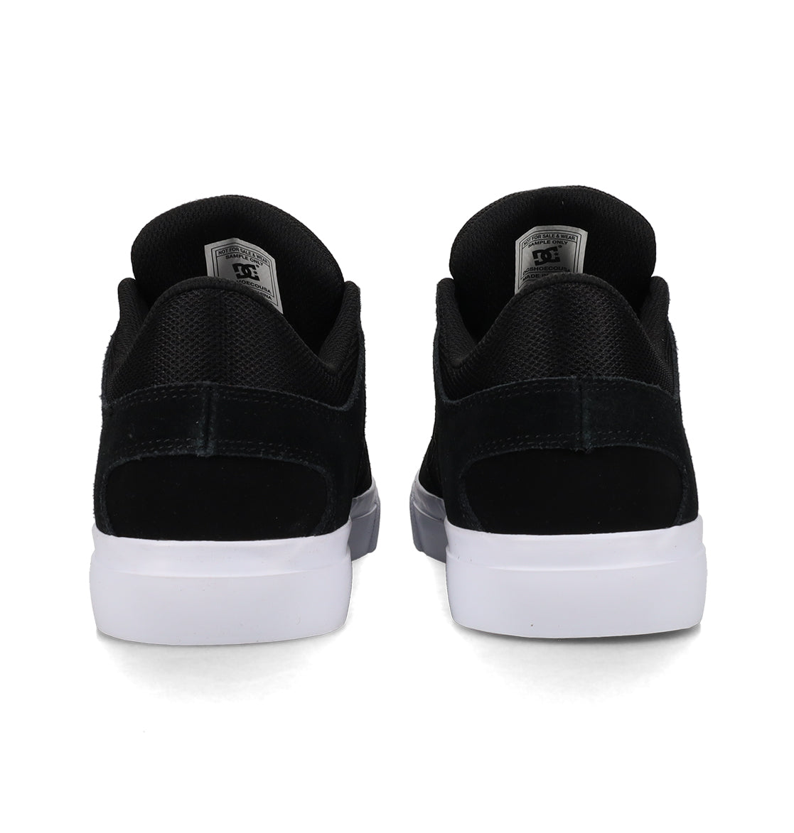 Back view of a pair of DC Shoes Men’s Onyx Shoes in black, featuring white soles. The sneakers are placed side by side, highlighting the heel, black mesh and suede textures, and a gray tag on each tongue. This minimal silhouette makes them an everyday go-to choice for both style and comfort.