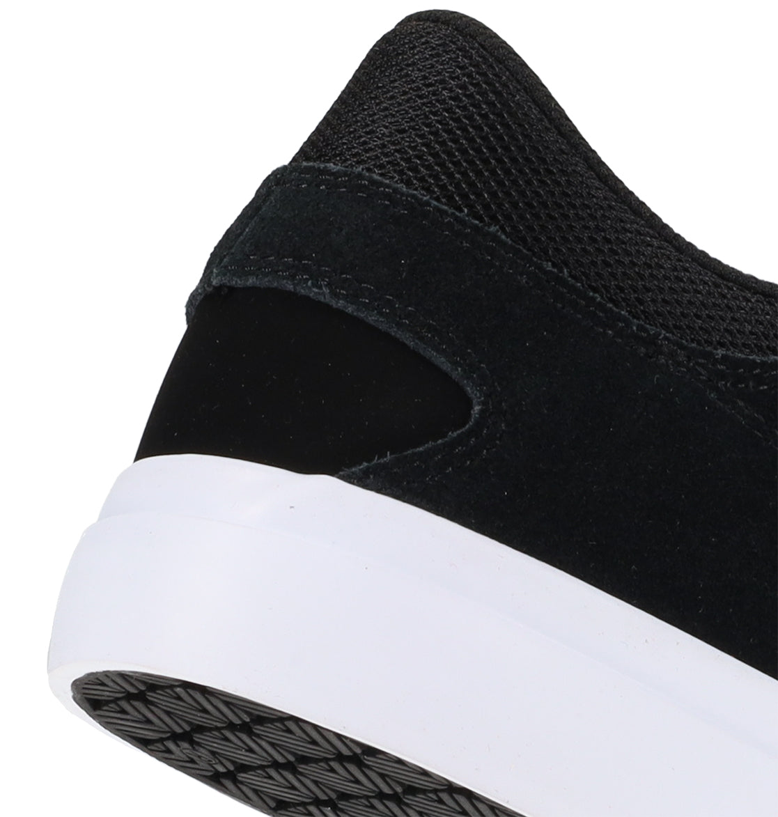 Close-up of the back and side of the Men’s Onyx Shoes by DC Shoes, showcasing a black sneaker with a white sole. The shoe combines suede and mesh textures in a sleek, minimal silhouette ideal for everyday wear. A patterned grip is visible on the heel of the sole.