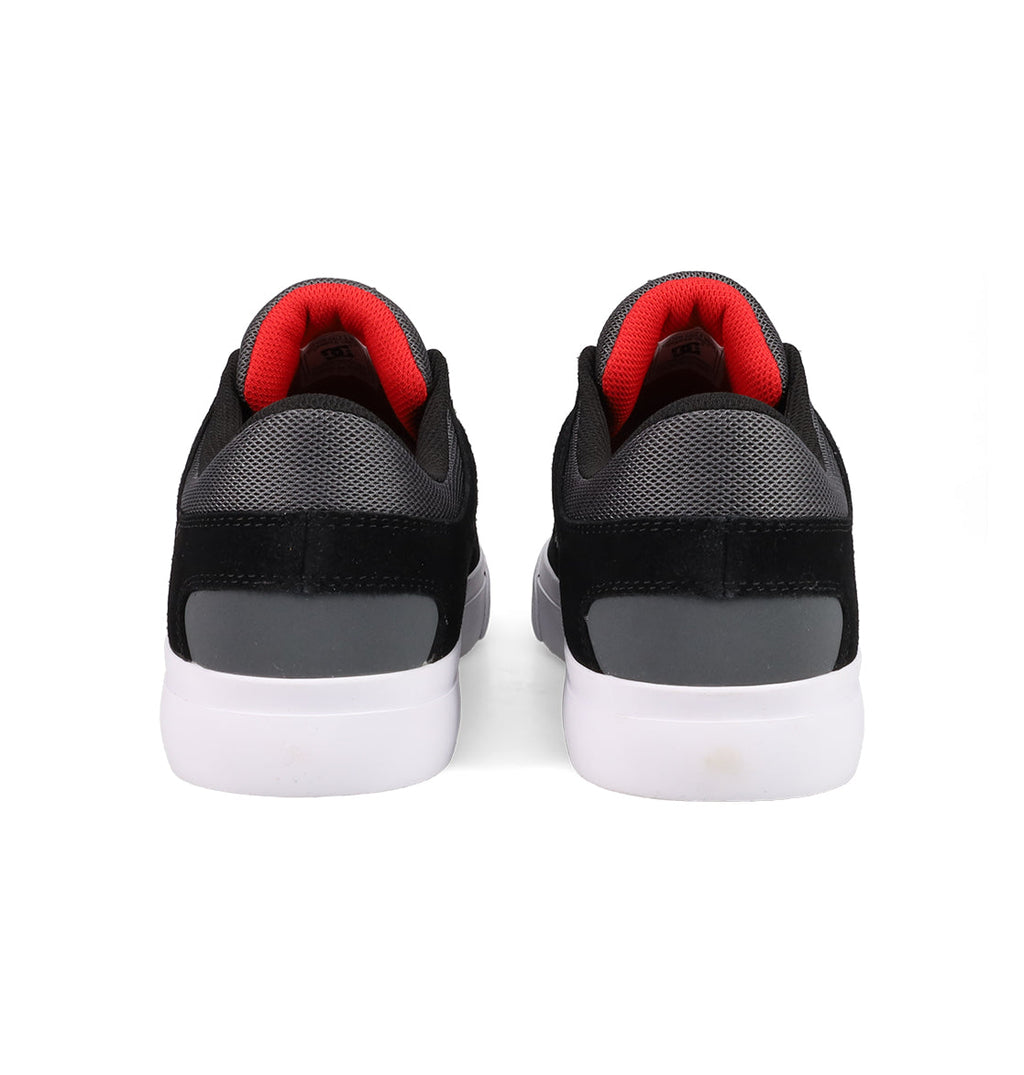 DC Shoes Men's Onyx Shoes in black and gray with white soles and red inner lining are displayed from the back, highlighting their minimal silhouette, against a plain white background.