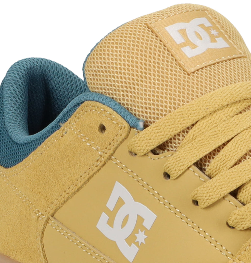 Close-up of the Men’s Onyx Skate Shoes by DC Shoes in yellow, featuring a white DC logo, matching yellow laces, and a teal inner lining. The mesh texture on the tongue accentuates the shoe’s streamlined silhouette.