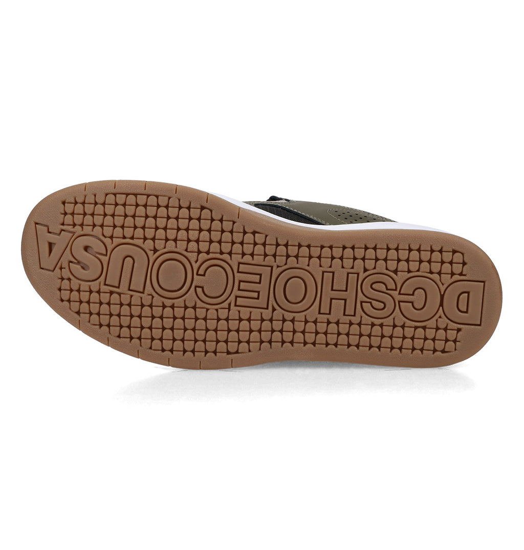 The sole of a Men’s Kalynx Zero Shoe from DC Shoes features a brown tread with raised, reversed “DCSHOECOUSA” text. Its tread pattern consists of small hexagons, and part of the shoe’s upper edge is visible—distinctive design details characteristic of DC Shoes.