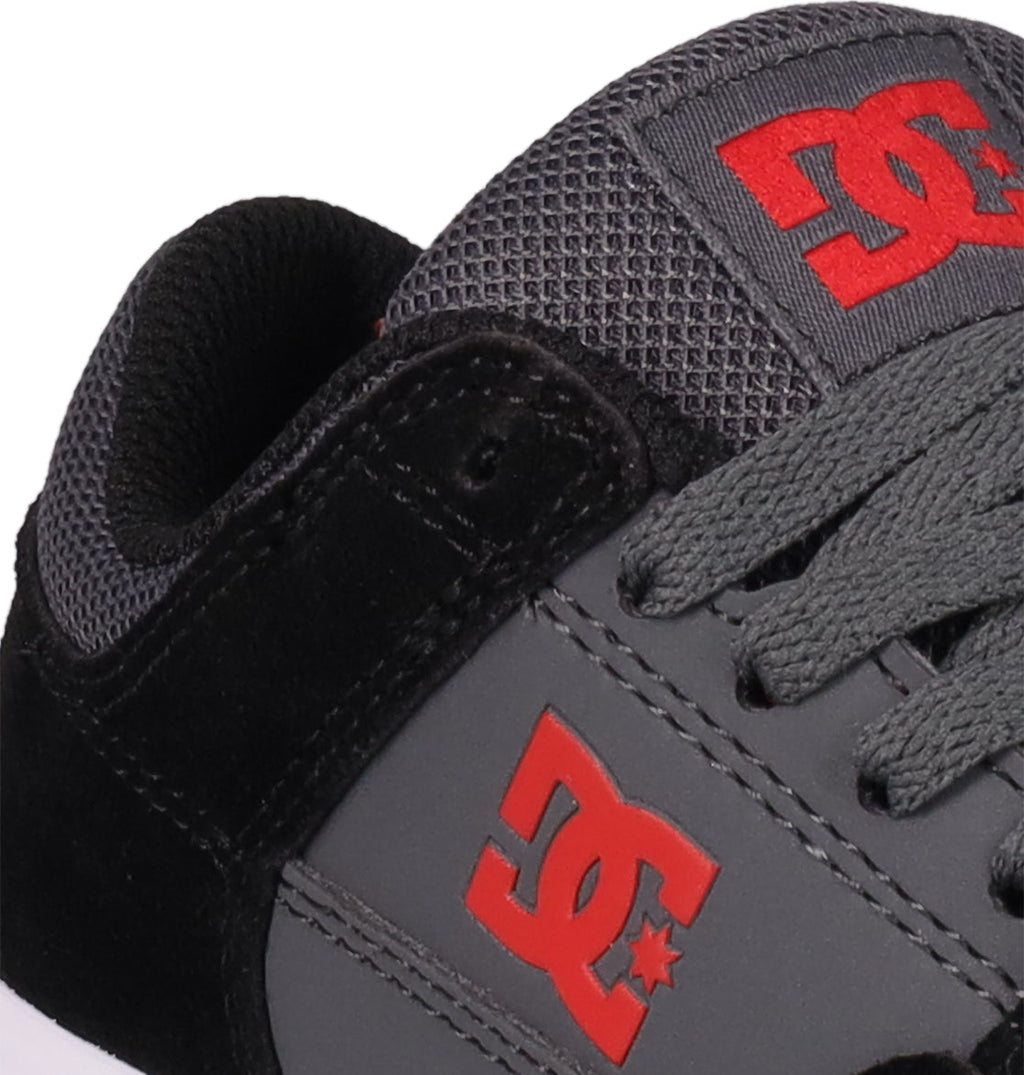 Close-up of DC Shoes Kids' Onyx, a black and gray sneaker with the red DC logo on the side and tongue, black laces, and mesh details—perfect for everyday wear.