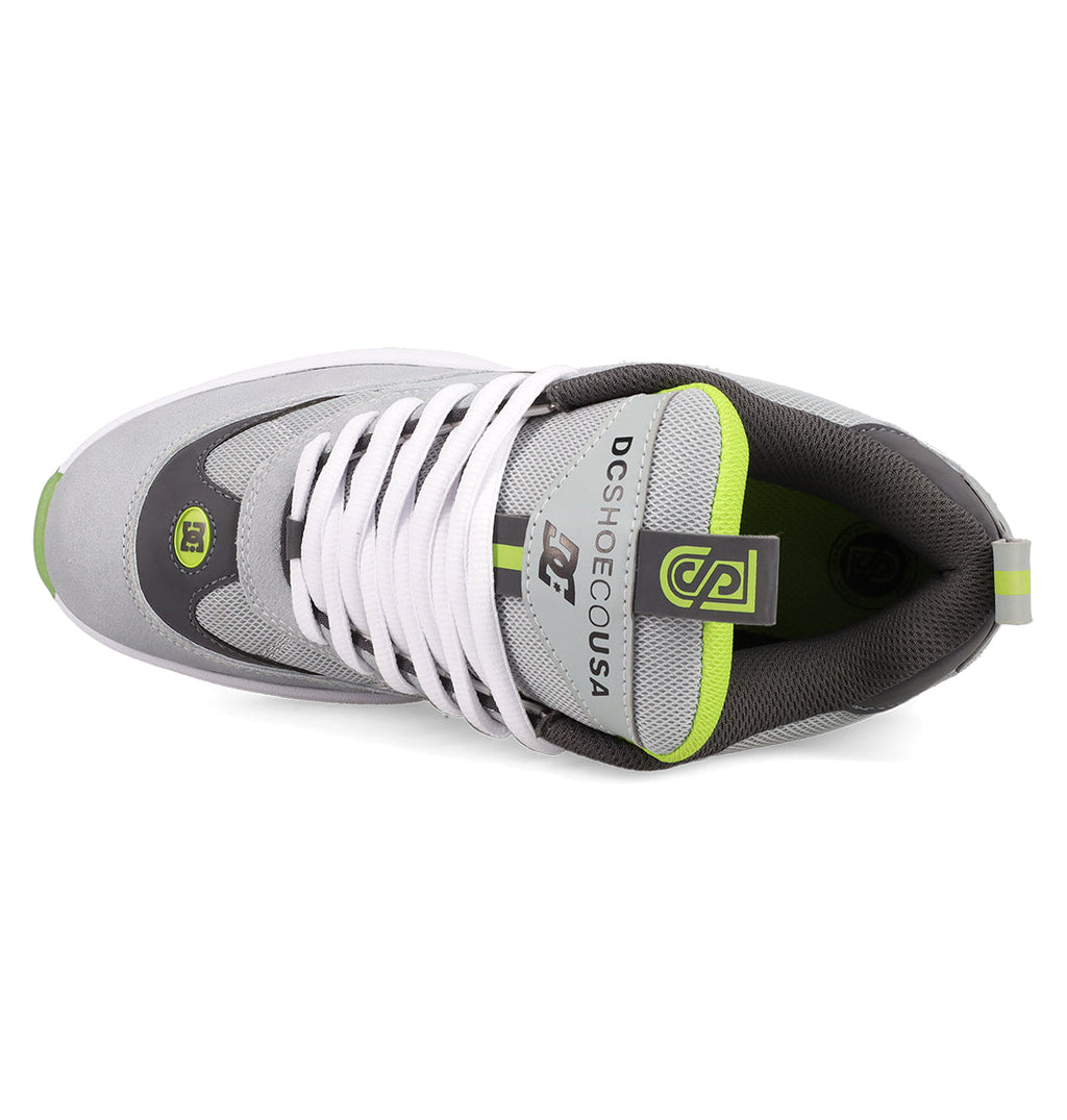 Top view of the Men's JS 2 Shoes by DC Shoes in gray and white with green accents, white laces, and DC SHOE CO USA branding on the tongue, showcasing heritage details inspired by John Shanahan's pro model.