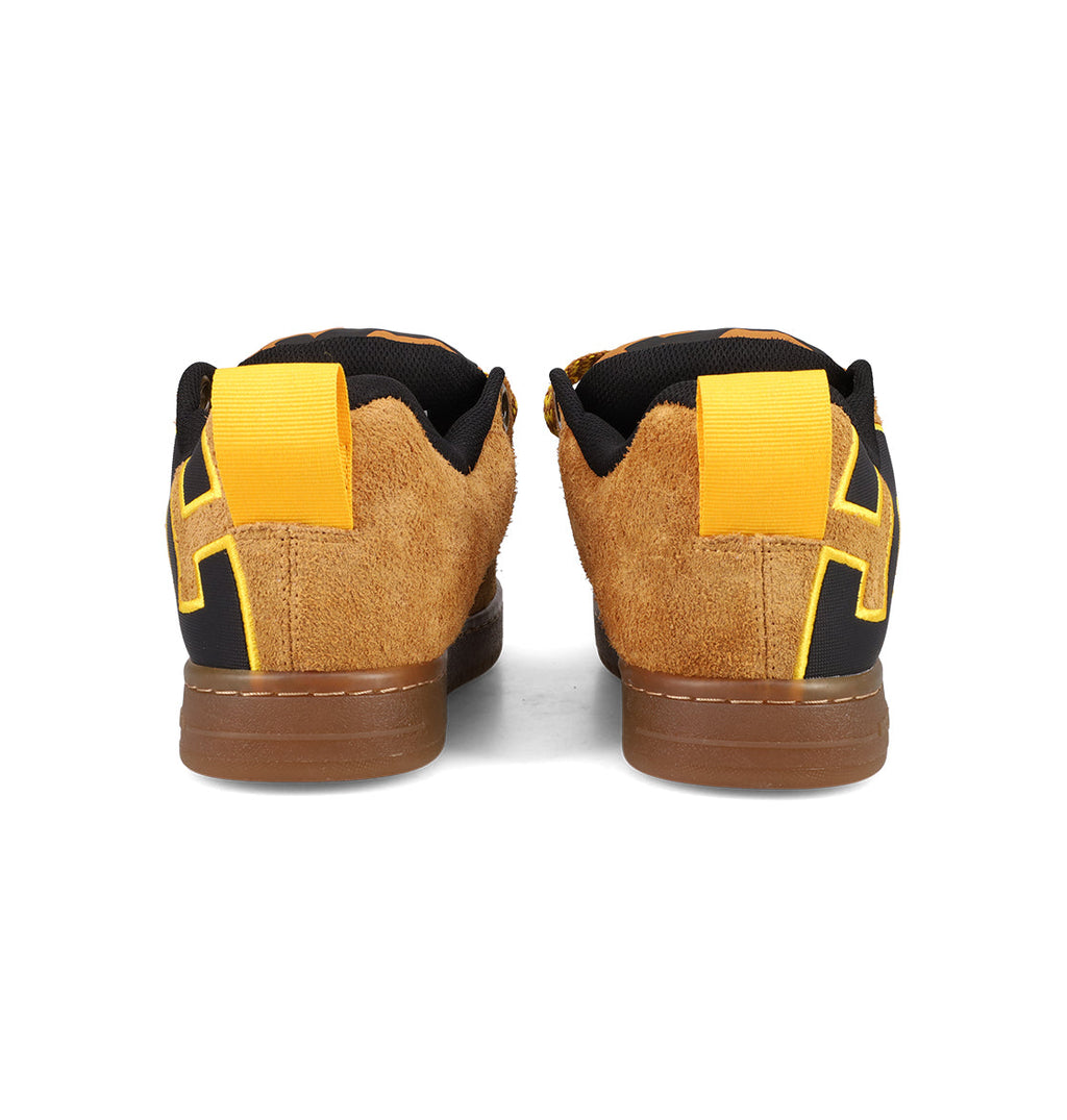The Men's Court Graffik Puff Shoes by DC Shoes are brown suede sneakers with yellow heel tabs, black accents, and bold yellow geometric designs on the heel, shown from the back against a white background for standout style.