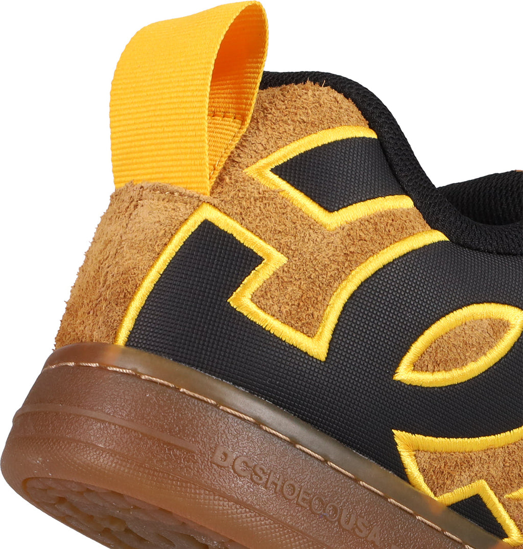 Close-up of the heel on DC Shoes Men's Court Graffik Puff Shoes, showcasing fresh colorways, brown suede, black fabric with large yellow embroidered letters, a yellow pull tab, and a brown rubber sole embossed with text.