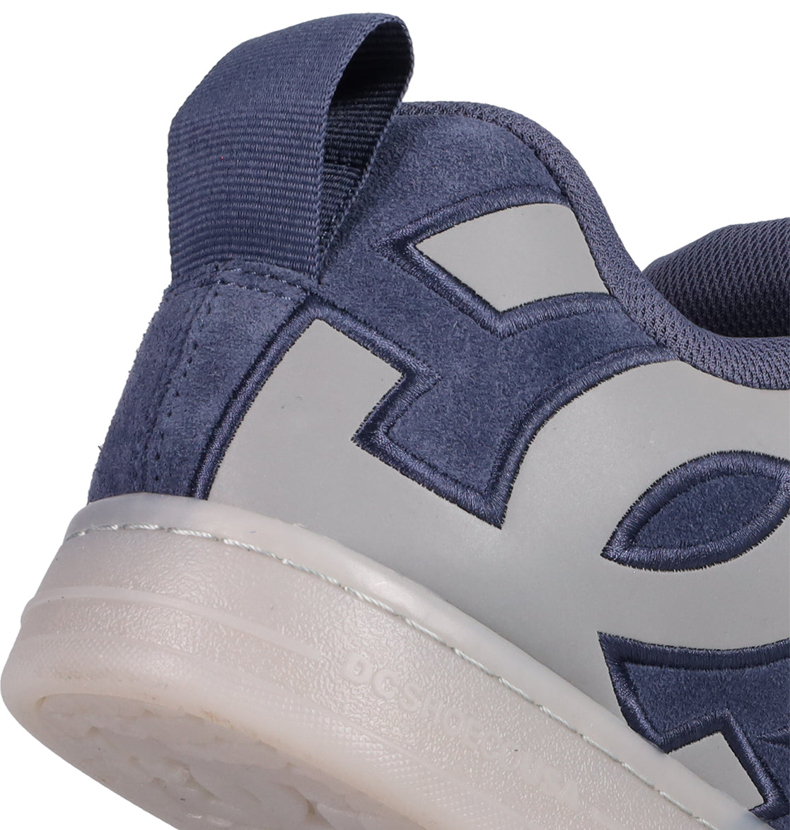 Close-up of the heel and side of DC Shoes Men's Court Graffik Shoes in blue and gray, featuring a textured pull tab, bold stitching, white rubber sole, and the signature puffy Court Graffik silhouette.