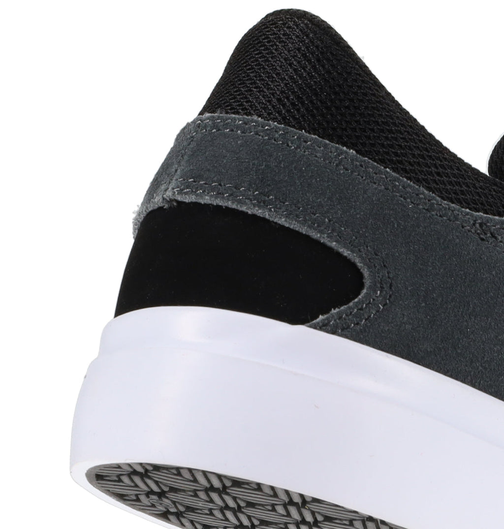 Close-up of the back heel of the DC Shoes Men’s Onyx Skate Shoes, featuring a minimal silhouette with a white sole, dark gray suede, black panel, and black mesh fabric at the top. The outsole has a textured pattern, giving these skate shoes a sleek yet durable finish.