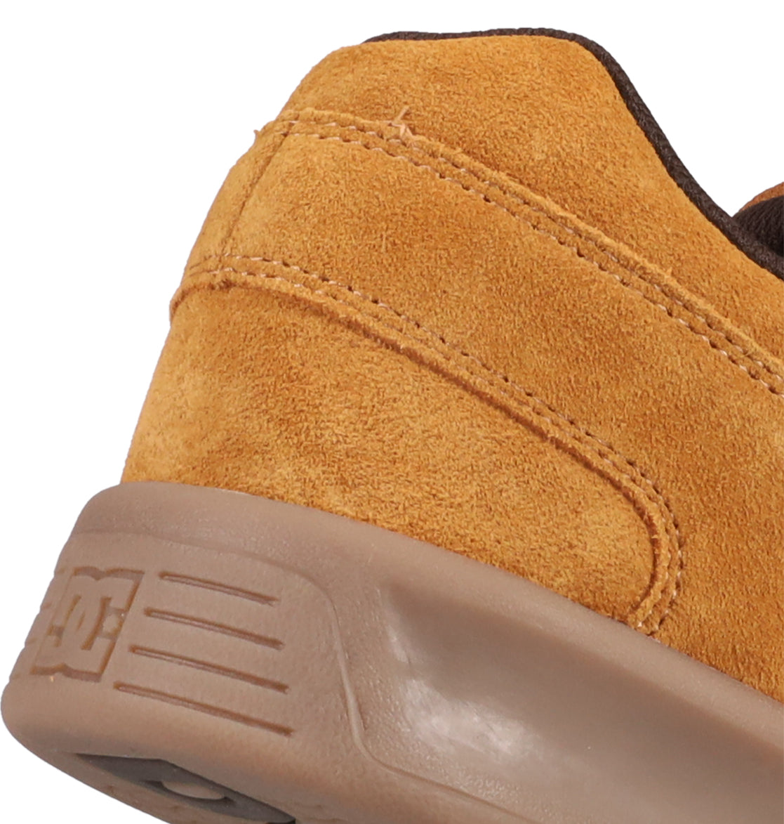 Close-up of the heel of a tan suede DC Shoes Men's Lynx Zero SE shoe with a brown rubber sole. Visible stitching and suede texture highlight the quality, with a subtle DC logo embossed on the side of the sole.
