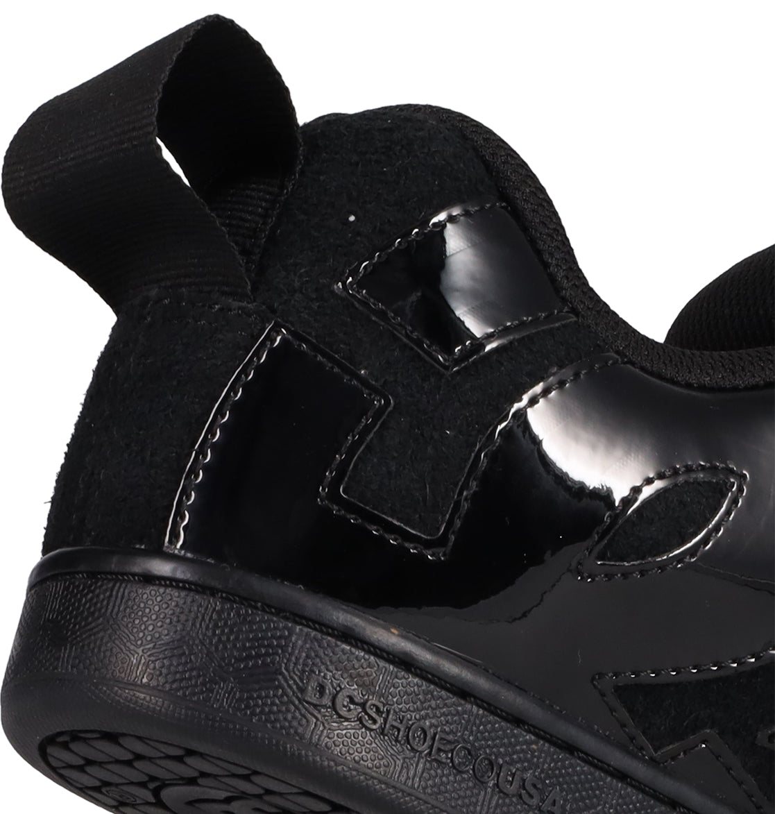 Close-up of the heel and side of DC Shoes Women's Court Graffik Puff Shoes in black, showcasing glossy and matte textures, stitched details, a fabric pull tab, and a textured rubber sole—bold statement sneakers from DC Shoes.