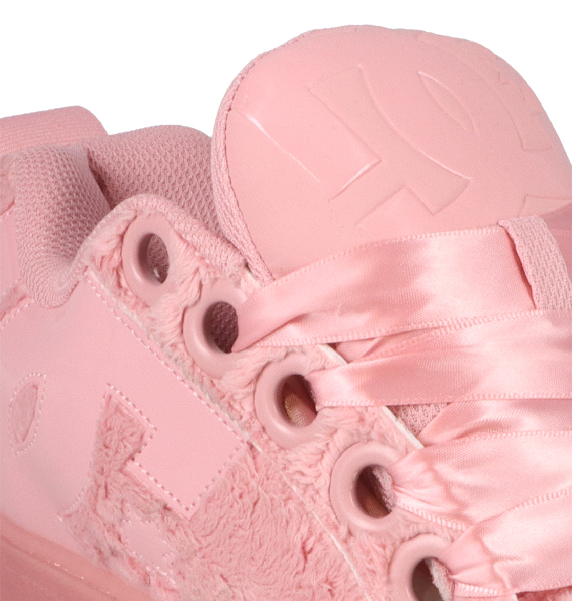 Close-up of the DC Shoes Women’s Court Graffik Puff sneaker in pink, featuring satin laces, embroidered and textured accents, and breathable mesh fabric near the ankle. The puffy tongue displays embossed lettering, showcasing a silhouette inspired by classic Court Graffik Puff fashion sneakers.