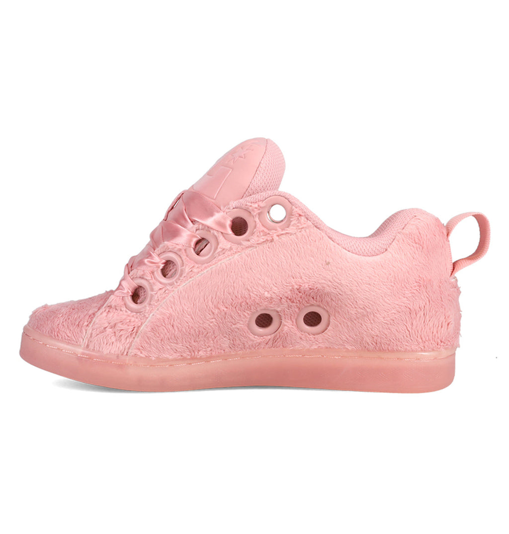 A side view of the Women’s Court Graffik Puff Shoes by DC Shoes showcases a light pink fashion sneaker crafted with a fuzzy, textured fabric and round ventilation holes along the side. The shoe features a puffy silhouette, complemented by matching pink sole, laces, and a heel loop.
