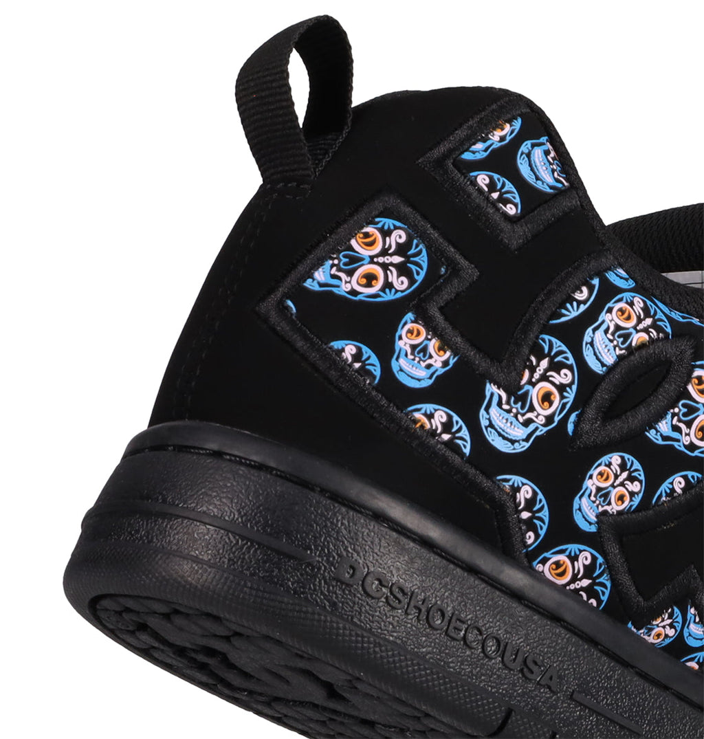 Close-up of the Men’s Court Graffik Day Of The Dead sneaker by DC Shoes, showcasing a bold, multicolored skull pattern inspired by Día de los Muertos on the side. This black shoe features a textured sole, a convenient heel loop for easy wearing, and the DC Shoes brand name embossed on the midsole.
