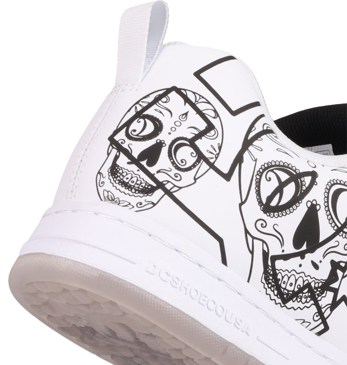 Close-up of the Men’s Court Graffik Day Of The Dead sneaker from DC Shoes, showcasing black line art of stylized skulls on the heel inspired by Día de los Muertos. This white sneaker also features a pull tab, textured sole, and a bold black “D” design detail.