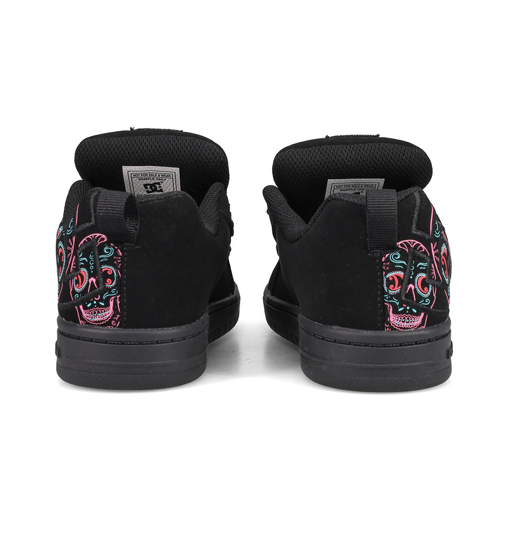 A pair of DC Shoes Kids’ Court Graffik Day Of The Dead sneakers, shown from the back, featuring colorful embroidered sugar skull designs on the heels. These black sneakers are inspired by Día de los Muertos and are part of the exclusive Day of the Dead Collection from DC Shoes.