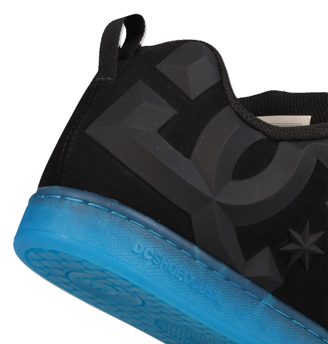 A close-up of the heel of the Women’s Court Graffik Beveled Shoes by DC Shoes, showcasing a large embossed DC logo and a vibrant blue translucent sole. The sneaker has a puffy silhouette with a black pull tab at the back.
