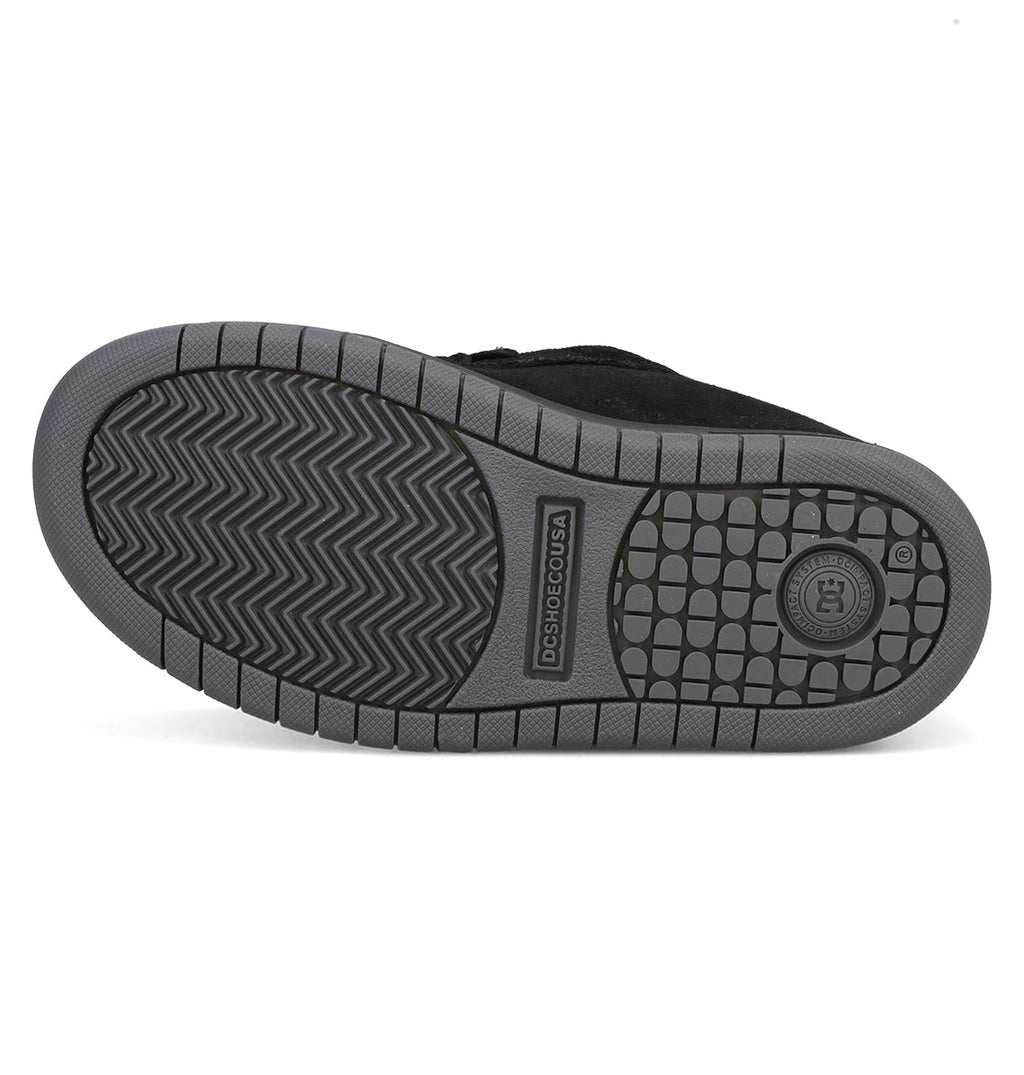 The image displays the gray rubber sole of the Kids’ Court Graffik Beveled Special Edition Shoes by DC Shoes, highlighting a herringbone tread pattern and circular logo accents that exemplify DC’s iconic branding and the shoe’s distinctive, puffy silhouette while ensuring excellent grip and standout style.