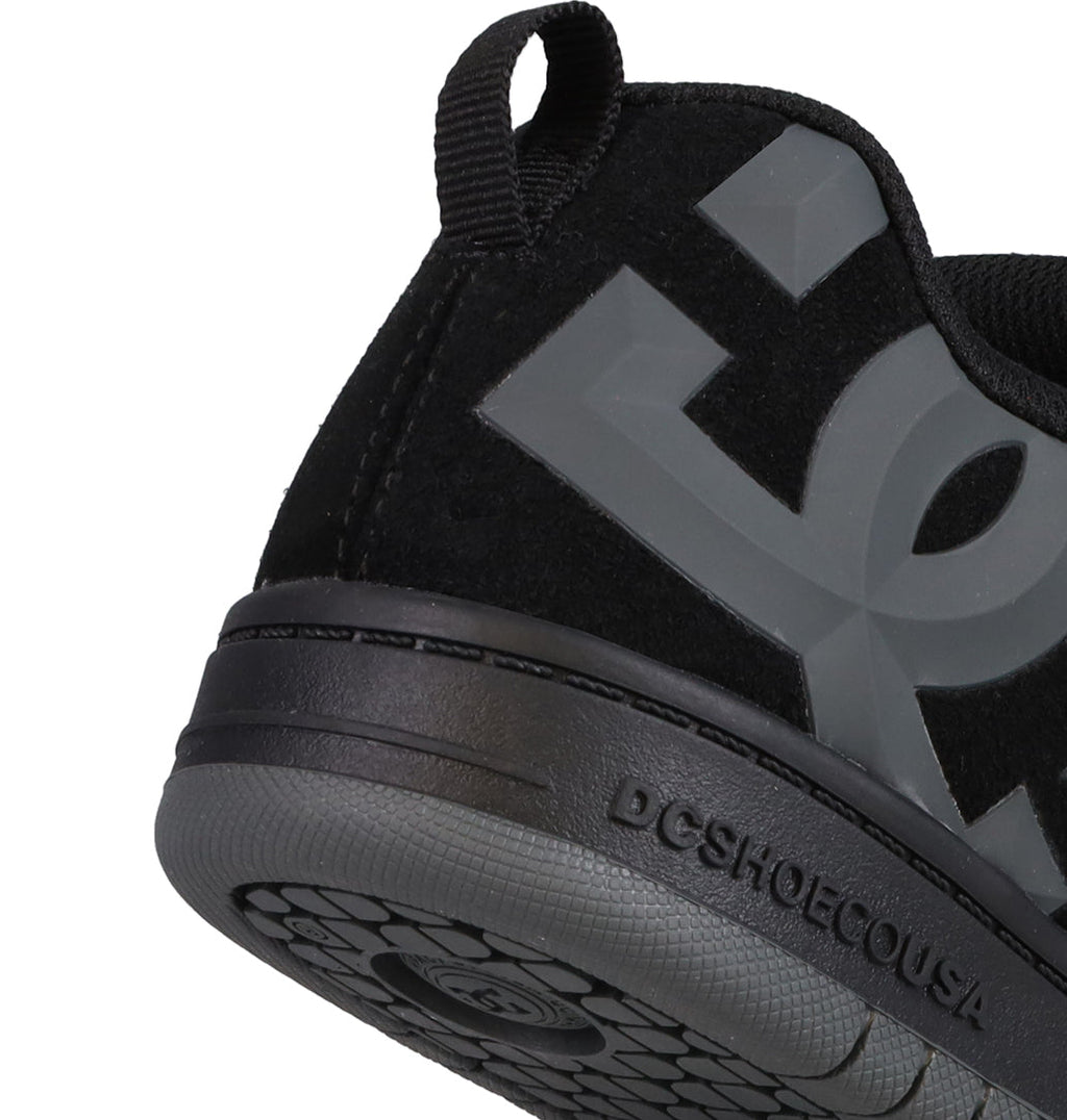 Close-up of the heel of a black DC Shoes Kids’ Court Graffik Beveled Special Edition sneaker, featuring a large gray DC logo, bold branding details, a practical pull tab, and “DCSHOECOUSA” embossed on the outsole. The signature puffy silhouette highlights the iconic Court Graffik Beveled design.