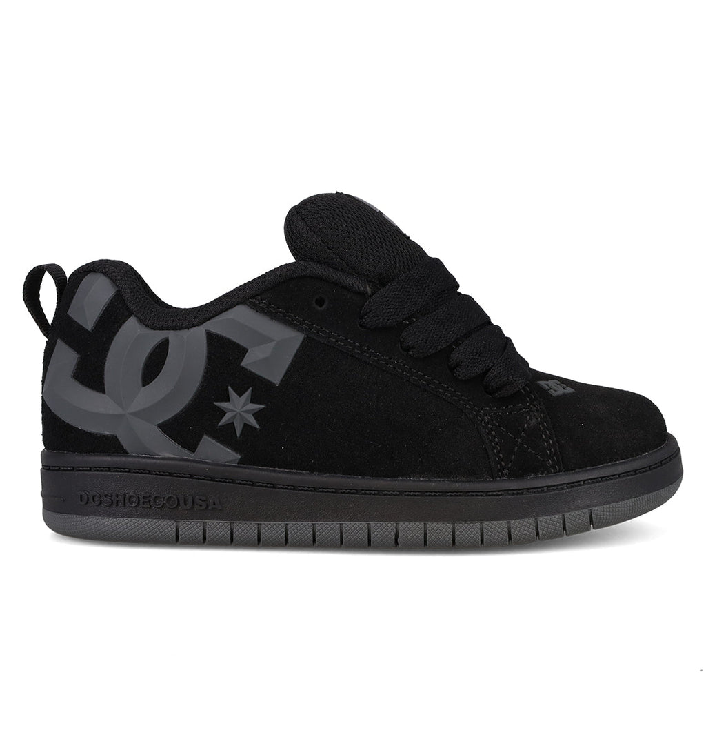 A side profile view of the DC Shoes Kids’ Court Graffik Beveled Special Edition features a black skate shoe with a puffy silhouette, thick laces, a large gray DC logo on the side, and a dark gray sole, displayed on a white background.