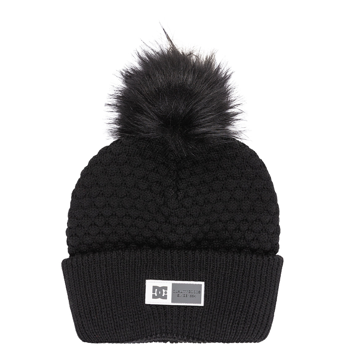 The Women’s Splendid Beanie by DC Shoes features a black knit, a textured pattern, wide folded brim, and a rectangular DC label on the front, finished with a large black faux fur pom-pom on top.