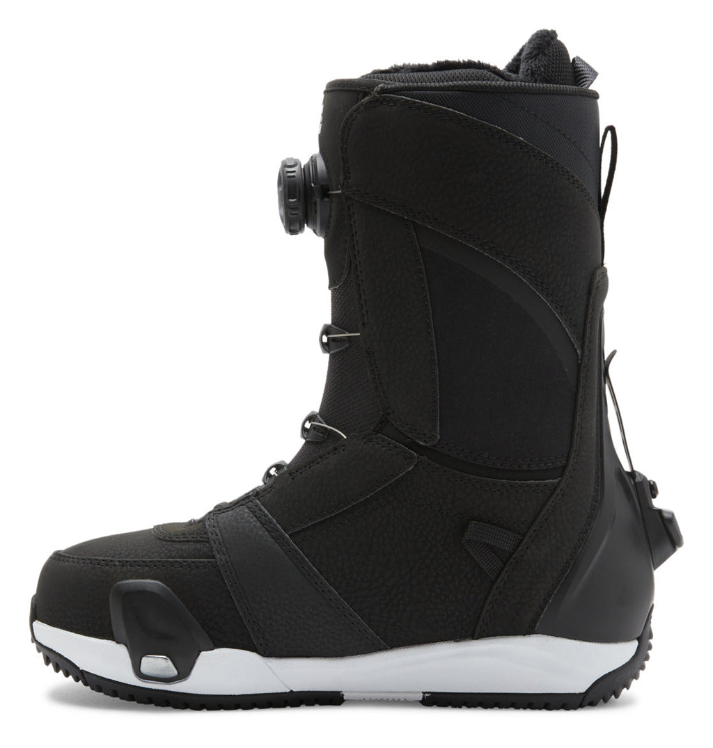 A side view of the DC Shoes Women’s Lotus Step On® Snowboard Boots in black with a white sole, showcasing the Dual Zone BOA Fit System dial lacing and reinforced heel and toe areas.