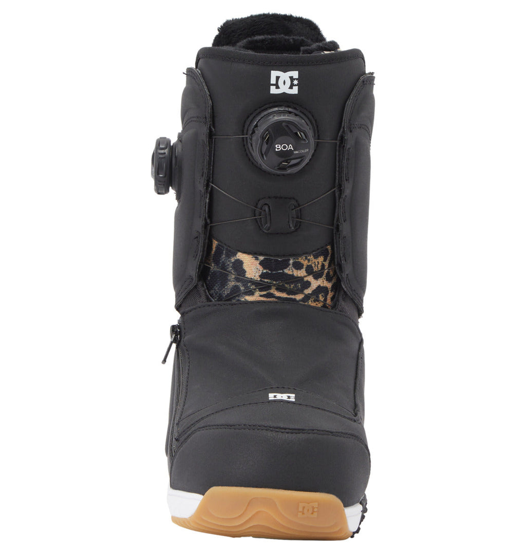 Front view of a black Women’s Mora BOA® Snowboard Boot by DC Shoes, featuring a tan sole, black and brown animal-print accents, and a round BOA® Fit System lacing knob on the tongue. The DC Shoes logo appears near the top and on the toe.