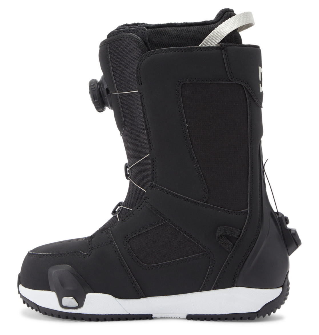 The DC Shoes Women’s Phase Pro Step On BOA® Snowboard Boots are shown in a profile view against a plain white background, featuring a black design with a white pull loop at the top, a side-mounted BOA® Fit System dial lacing system, and a thick, textured sole in white and black.