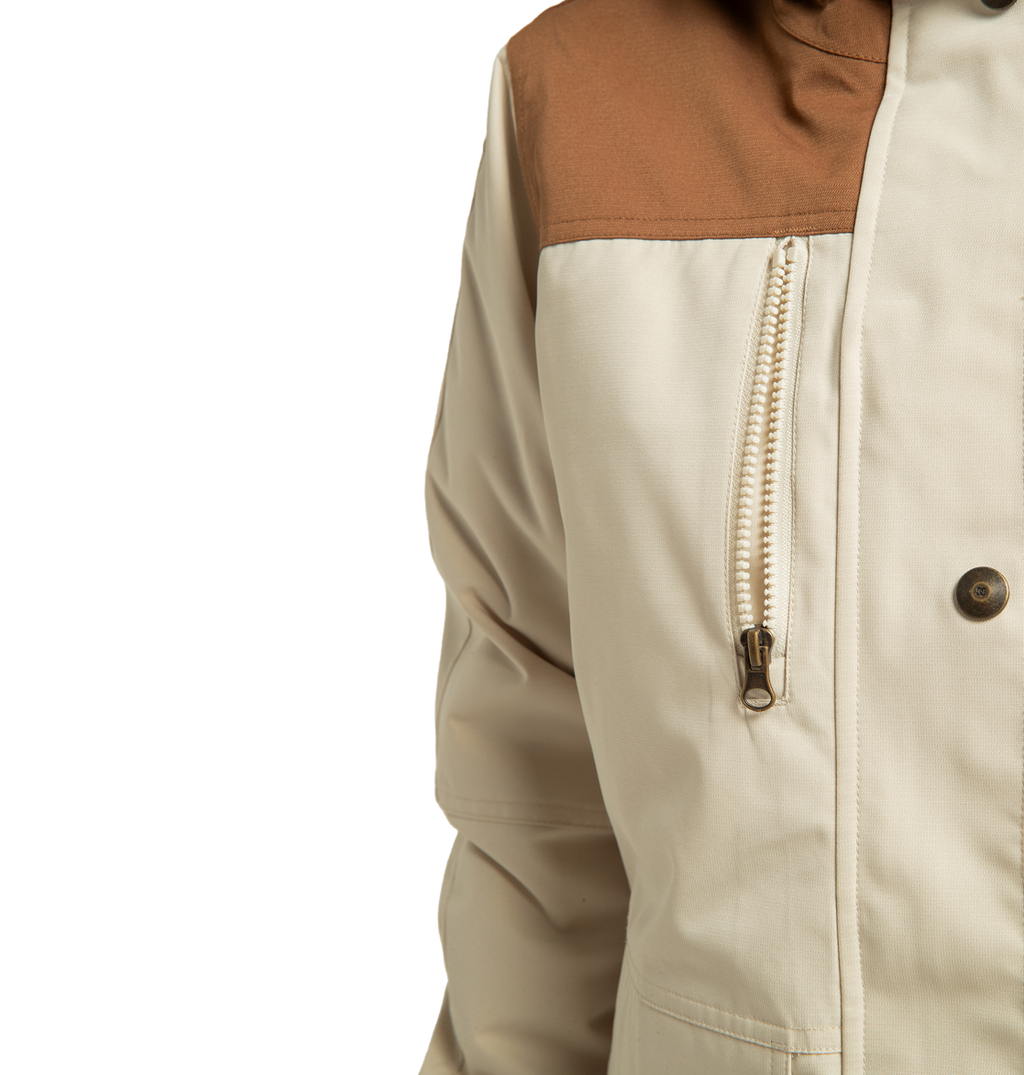 Close-up of the DC Shoes Women’s Liberate Insulated Jacket in beige, showcasing a contrasting brown shoulder panel, a chest zipper, and a single visible button. Made from recycled polyester, this jacket is built to deliver both style and warmth for your next winter adventure. The image is set against a plain white background.