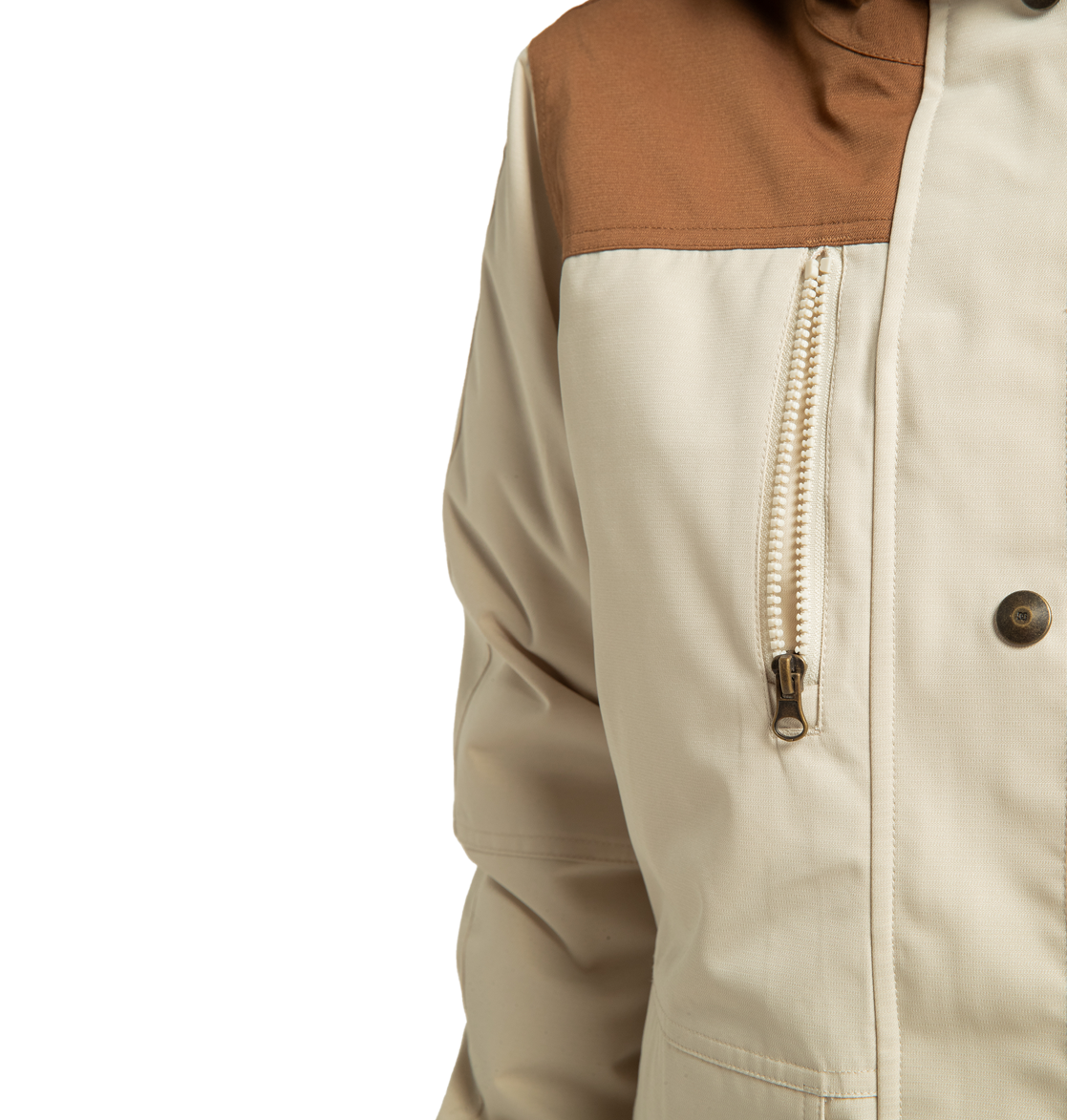 Close-up of the DC Shoes Women’s Liberate Insulated Jacket in beige, showcasing a contrasting brown shoulder panel, a chest zipper, and a single visible button. Made from recycled polyester, this jacket is built to deliver both style and warmth for your next winter adventure. The image is set against a plain white background.