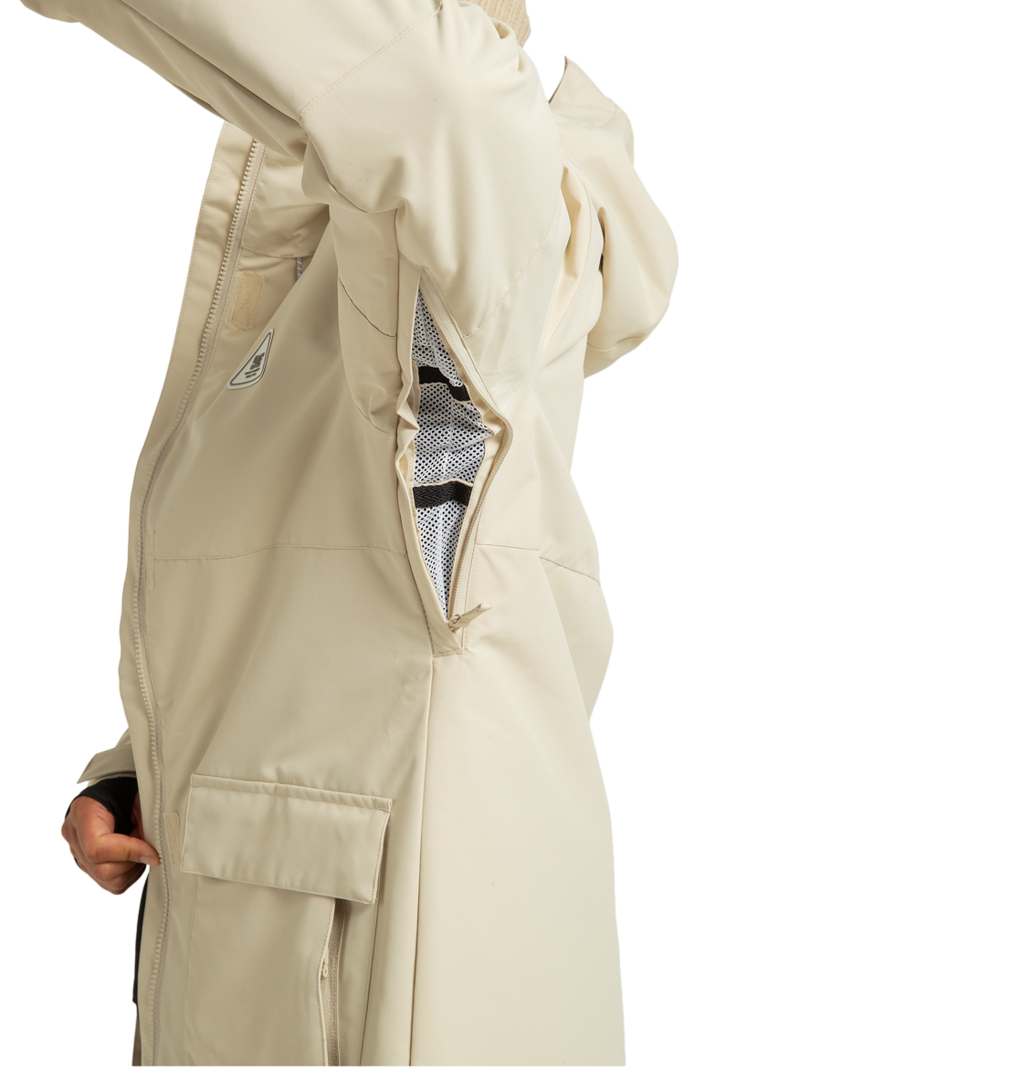 A person in a beige DC Shoes Women’s Cruiser Insulated Jacket displays a large zippered underarm vent with mesh lining. This recycled polyester jacket from DC Shoes features a flap pocket and a small side logo, merging practical weather defense technology with sustainable style.
