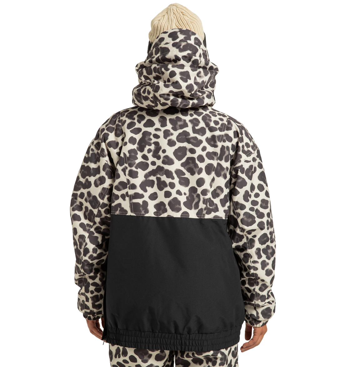 A person is shown from the back against a plain white background, wearing the DC Shoes Women’s Chalet Anorak Insulated Jacket featuring an animal print with a black lower half and a hood, paired with matching pants and a cream knit hat.