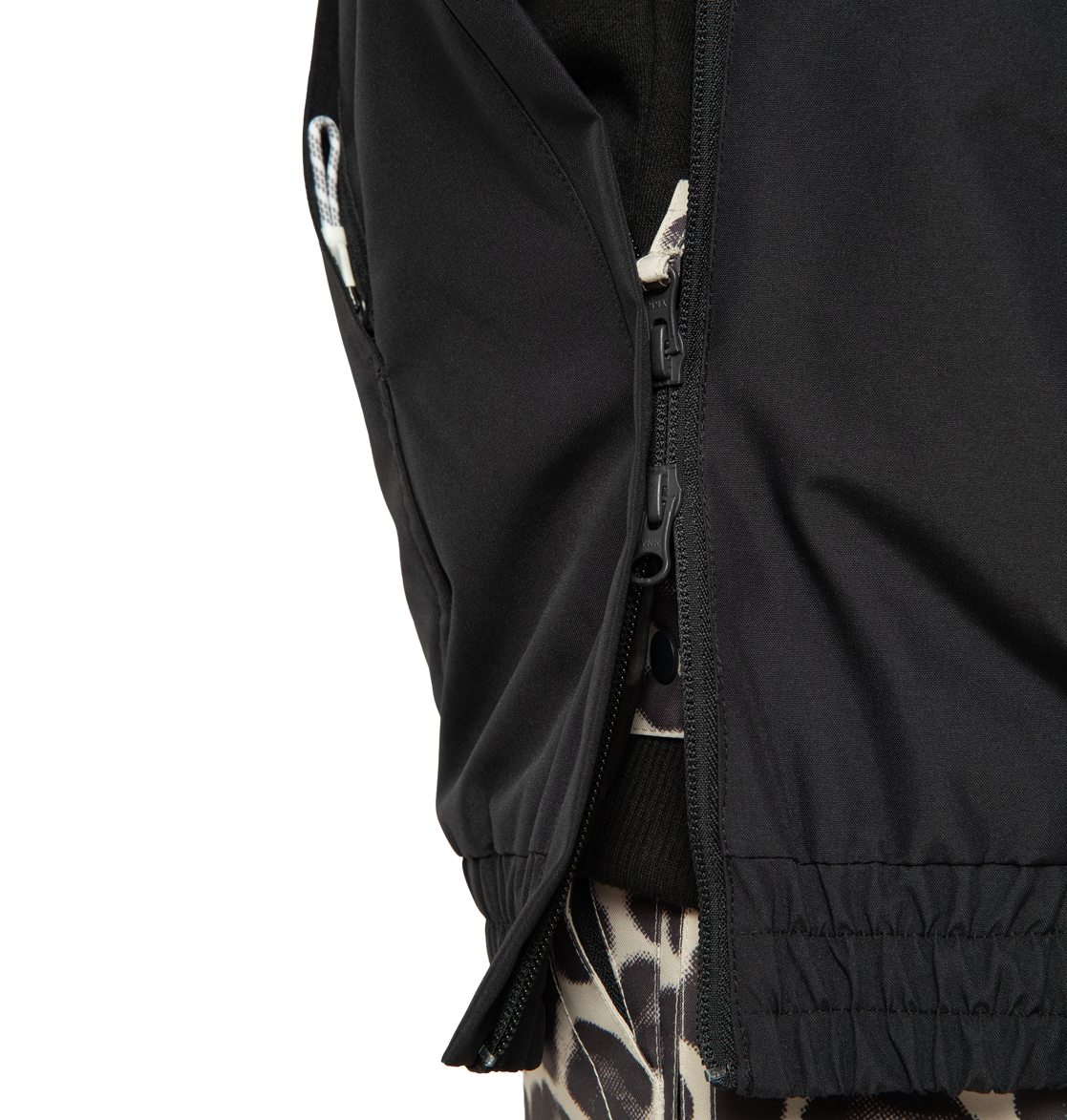Close-up of the DC Shoes Women’s Chalet Anorak Insulated Jacket in black, with the zipper partially open to reveal a garment underneath featuring a black and beige giraffe print pattern.
