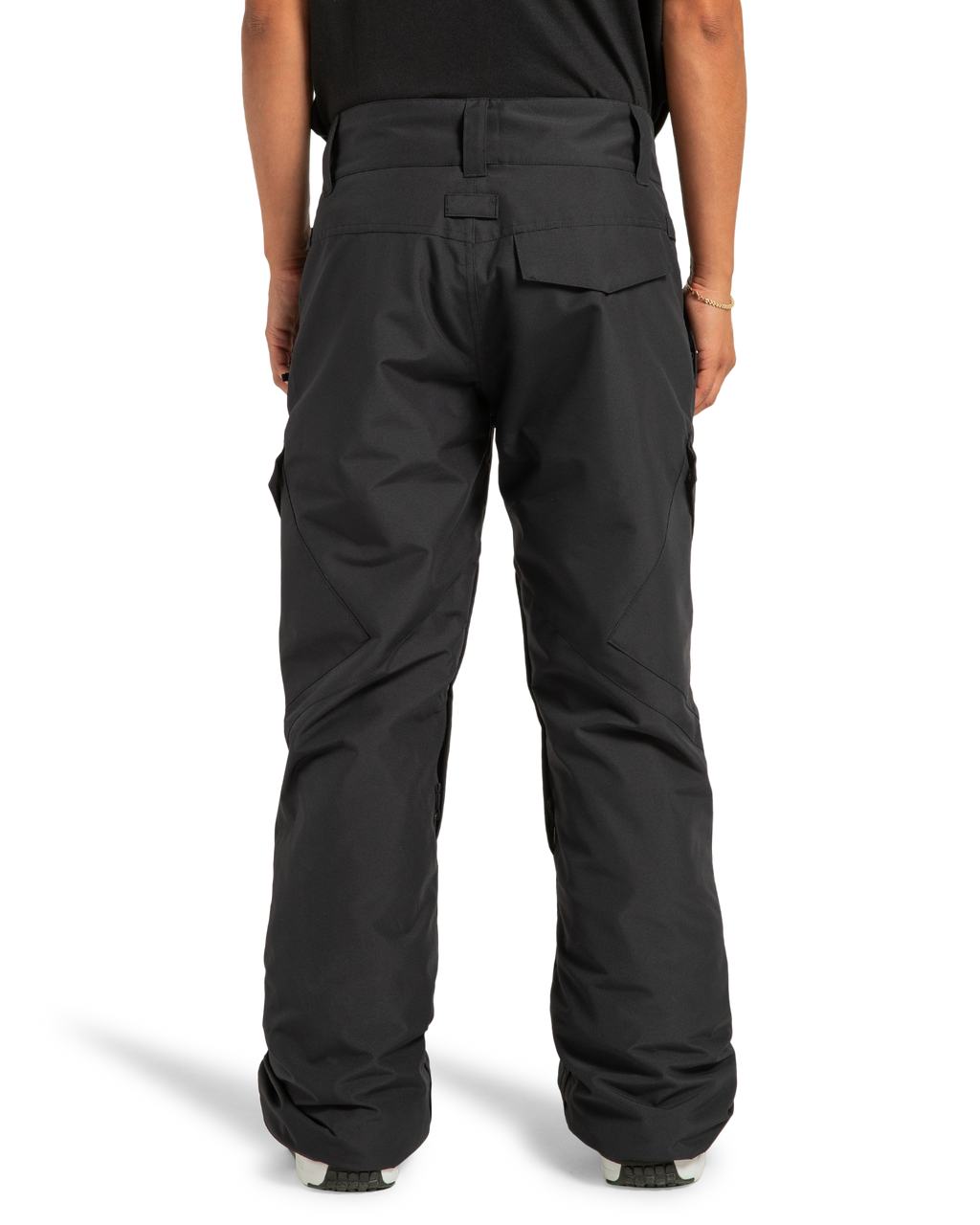 A person is seen from the back wearing loose-fitting black DC Shoes Women’s Nonchalant Insulated Snow Pants, which feature multiple pockets and are designed for outdoor or winter activities. These women’s snow pants are made with recycled polyester fabric and PROFILL insulation. The person is also wearing a black shirt.