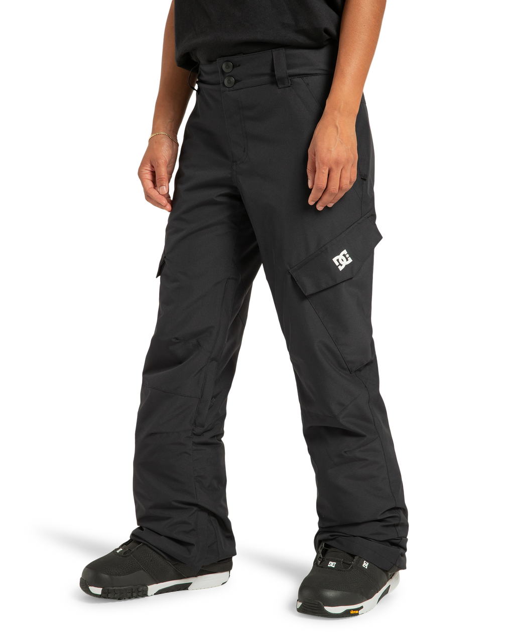 A person wearing DC Shoes Women’s Nonchalant Insulated Snow Pants—crafted from recycled polyester material and featuring PROFILL insulation—with black snow boots and a black shirt, stands against a white background.