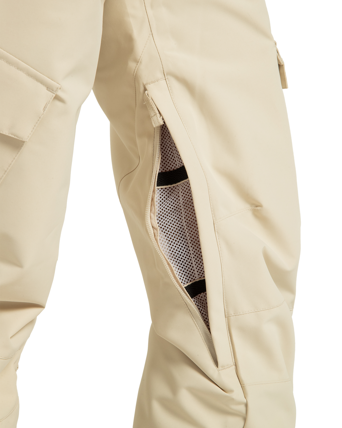 Close-up of beige DC Shoes Women’s Nonchalant Insulated Snow Pants, featuring a partially open zippered mesh-lined vent along the thigh for ventilation and a cargo pocket on the side. Made from recycled polyester, these snow pants combine insulation, style, and sustainability.